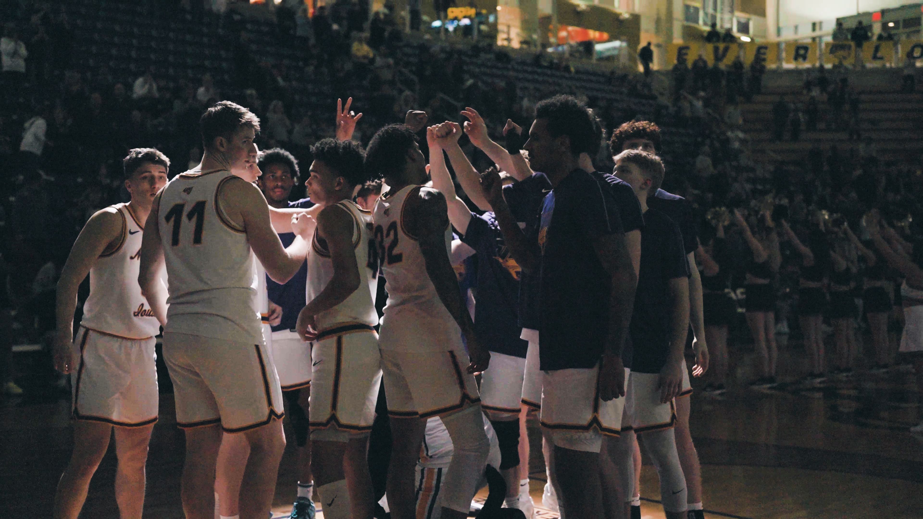 College basketball team huddled under a spotlight