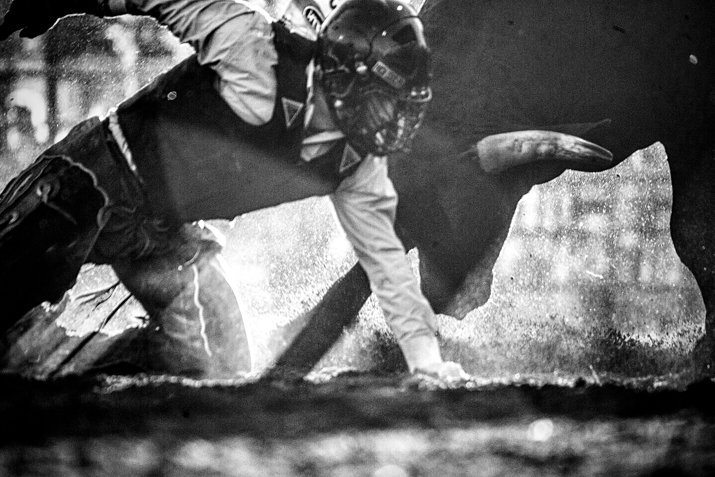 Black and white close-up of a bull rider in the dust