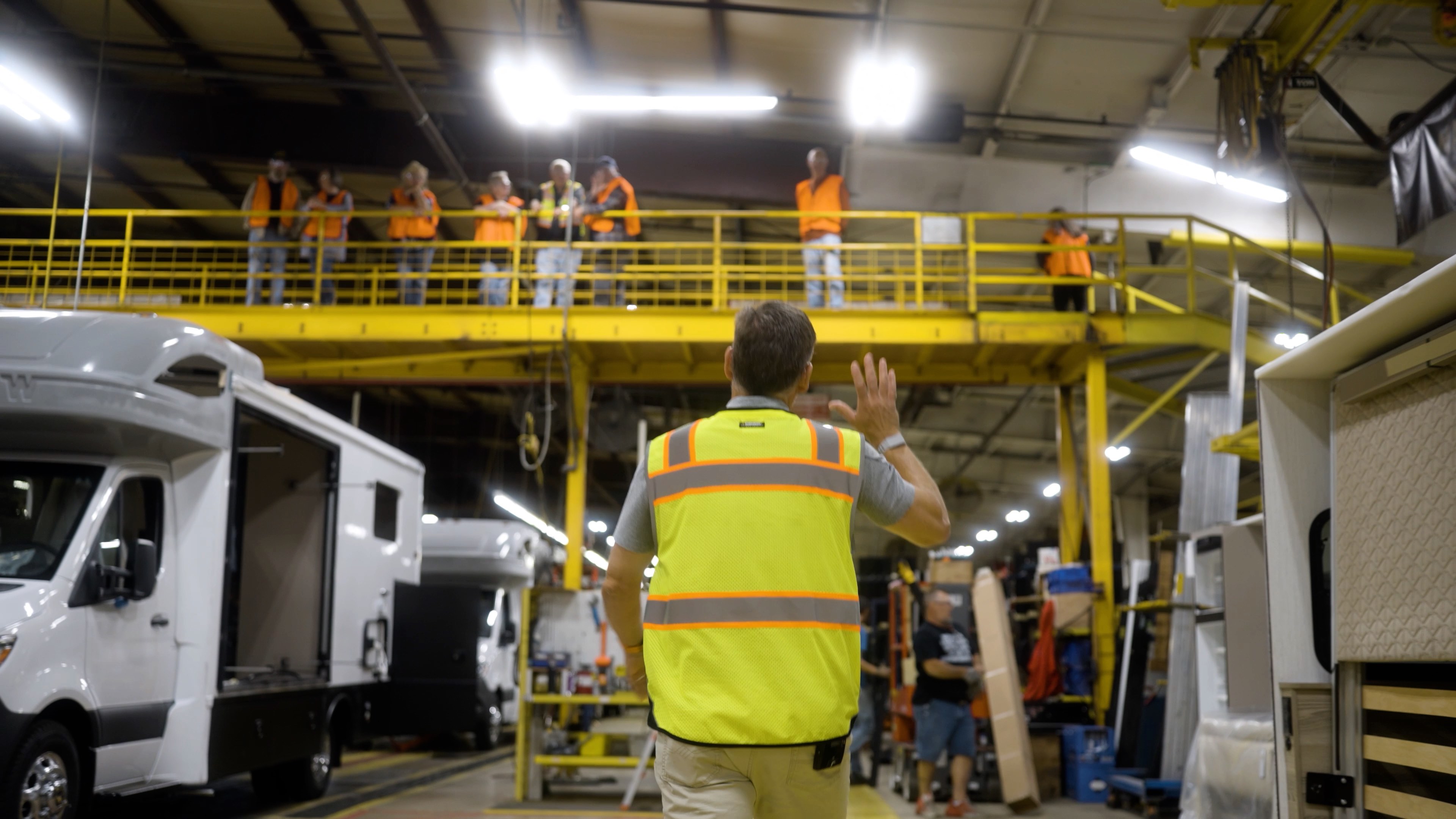 Guide leading a factory tour on a yellow mezzanine