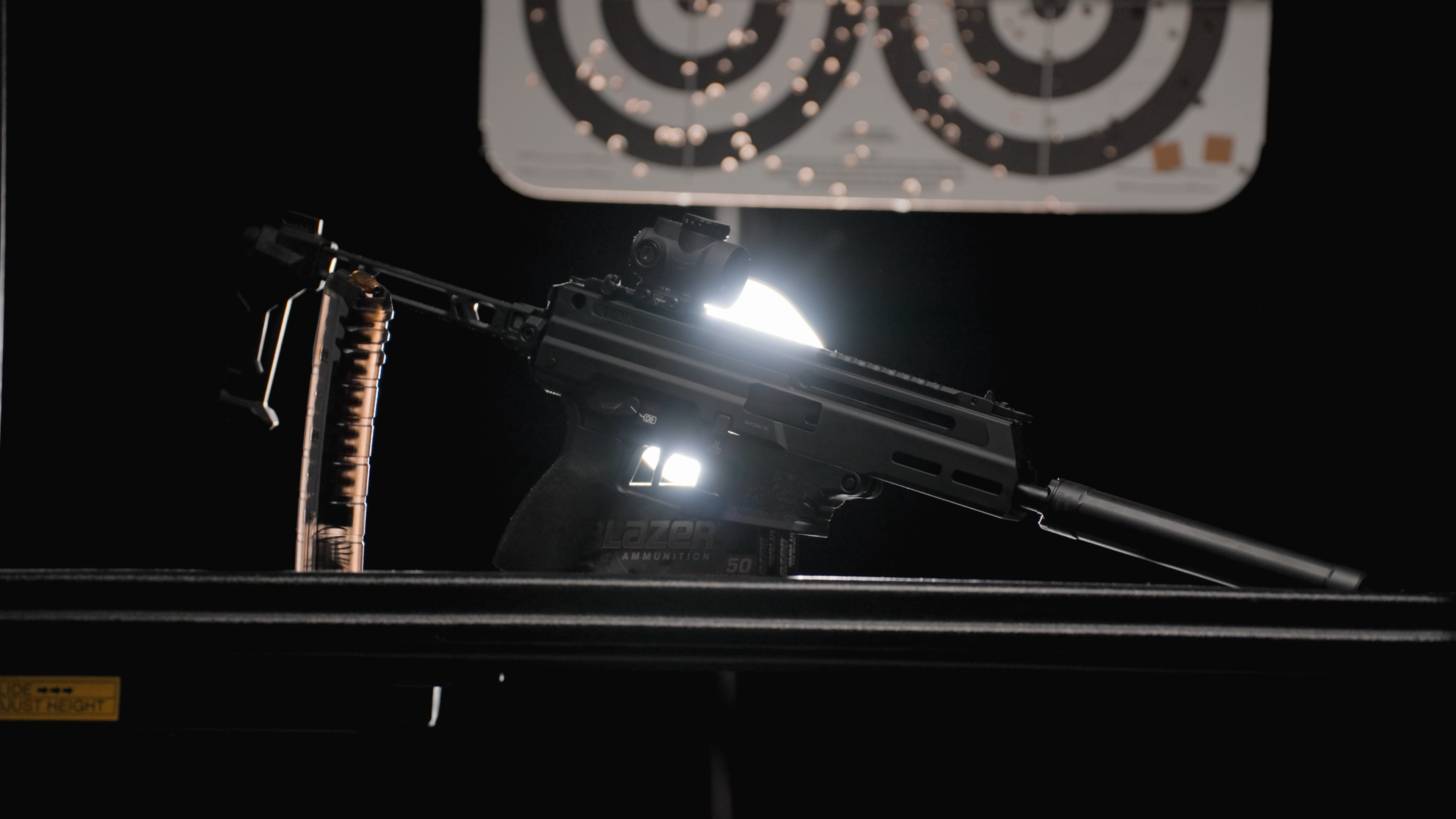 Suppressed pistol lit dramatically at an indoor range