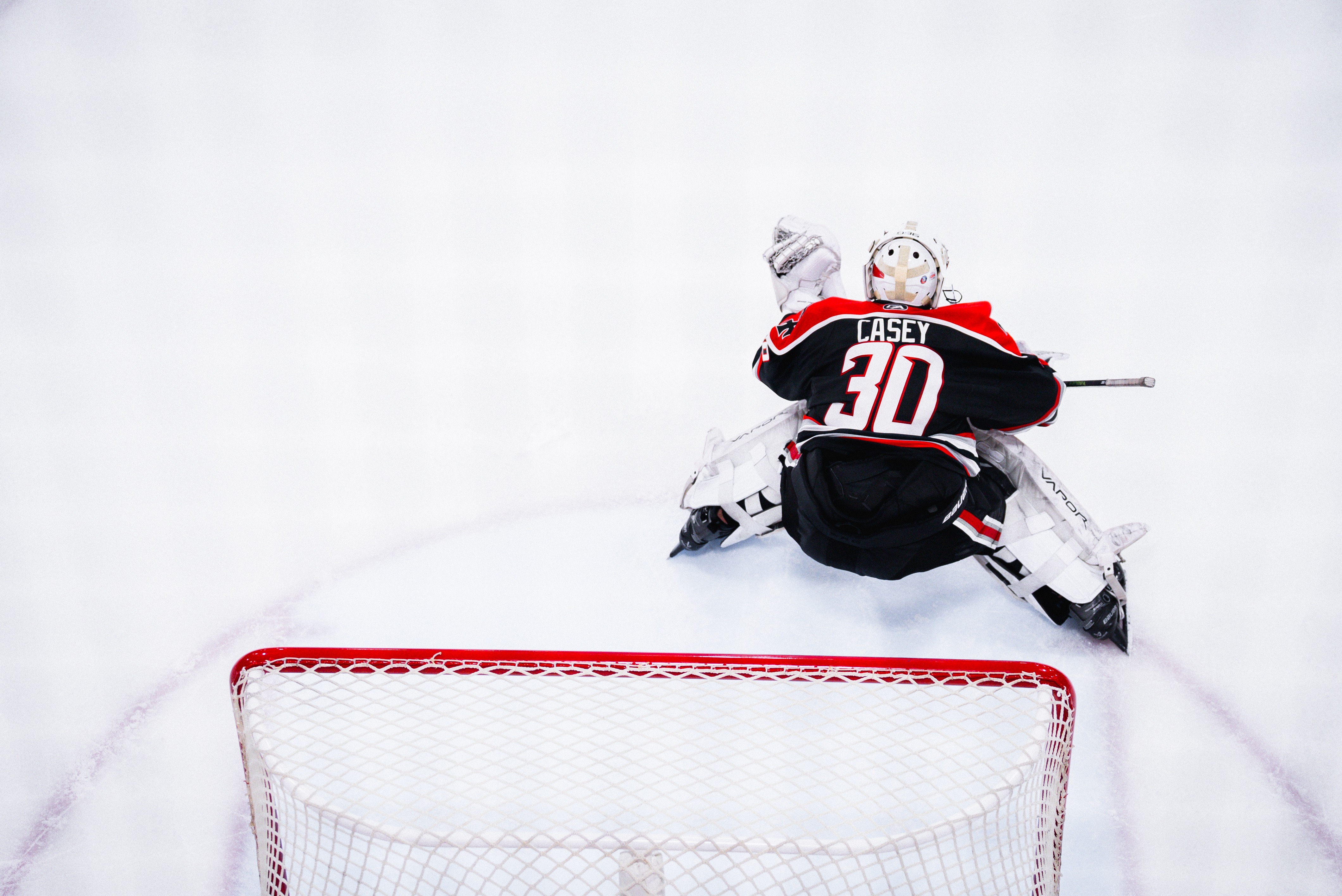 Hockey goalie stretching on clean white ice