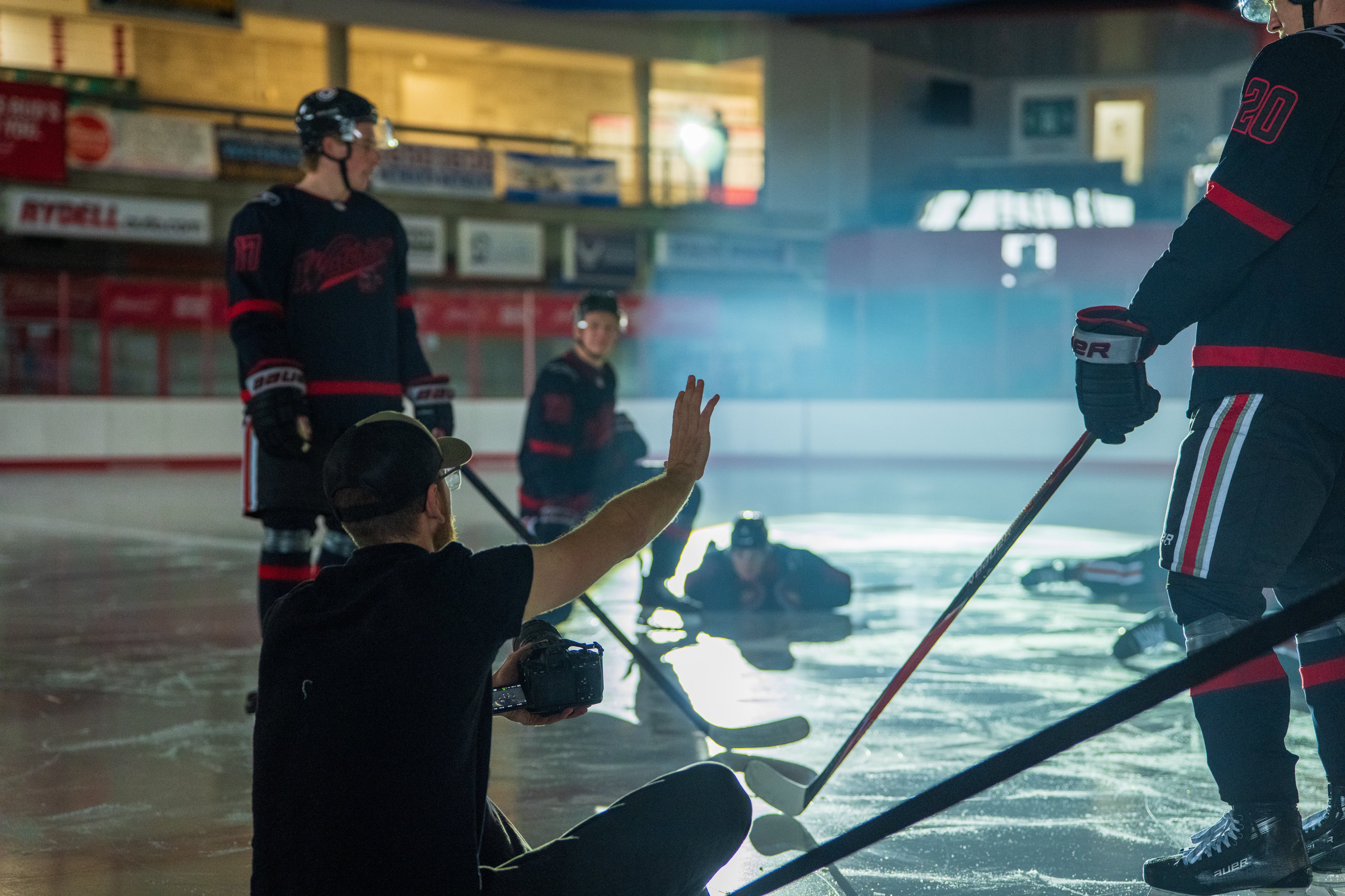 John Lockwood directing a hockey shoot from the ice, camera in hand